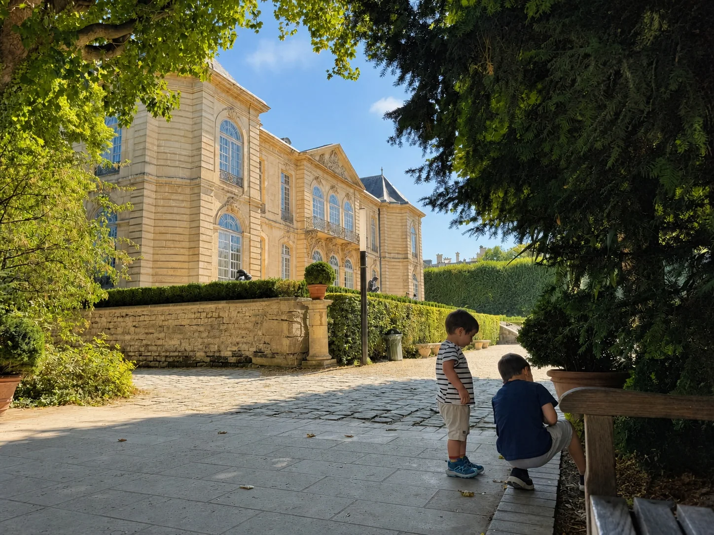 Two children exploring a sunny garden beside a historic building